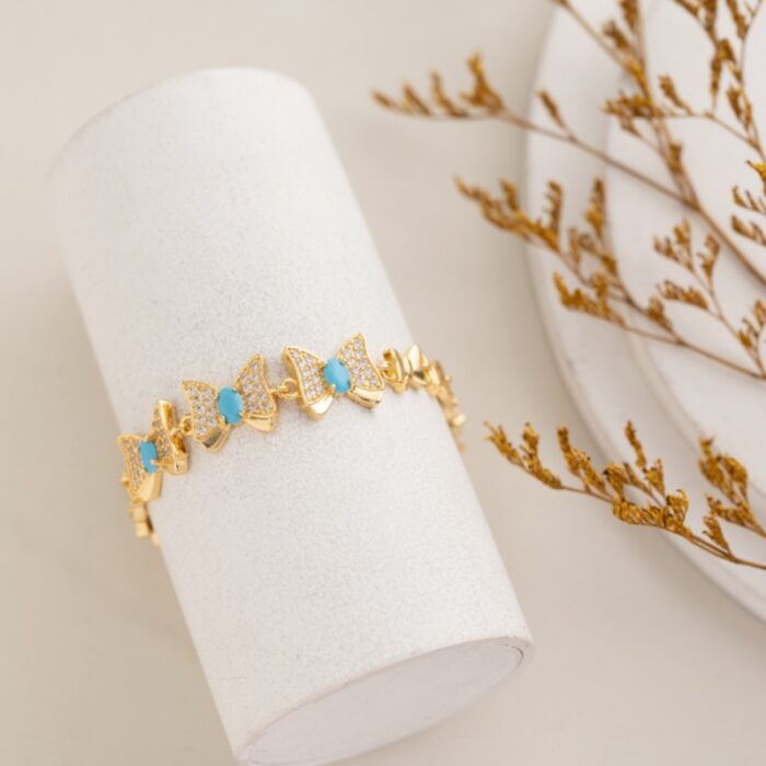 10336435_67dc584119141 سوار ذهبي بتصميم فيونكة مع زركون أبيض وأزرق - الصورة 1