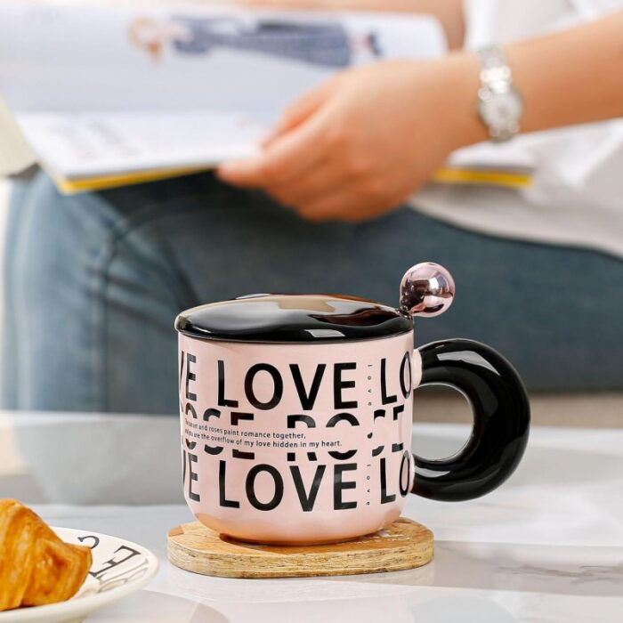 ⁦مج (كوب ) مع غطاء وملعقة لون أسود وزهري⁩ - الصورة ⁦2⁩