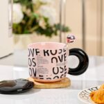 ⁦مج (كوب ) مع غطاء وملعقة لون أسود وزهري⁩ - الصورة ⁦3⁩