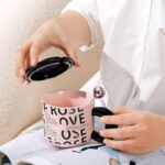 ⁦مج (كوب ) مع غطاء وملعقة لون أسود وزهري⁩ - الصورة ⁦5⁩