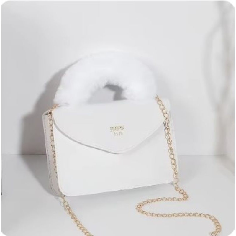 ⁦شنطة صغيرة للصبايا  والاطفال  انيقة من الفرو الصناعي الناعم بمقبض يد علوي وسلسة كتف ذهبية -  تصميم أنيق ولطيف - ارتفاع 15 سم وعرض 21 سم - لون أبيض⁩ - الصورة ⁦1⁩