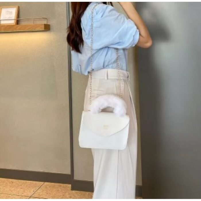 ⁦شنطة صغيرة للصبايا  والاطفال  انيقة من الفرو الصناعي الناعم بمقبض يد علوي وسلسة كتف ذهبية -  تصميم أنيق ولطيف - ارتفاع 15 سم وعرض 21 سم - لون أبيض⁩ - الصورة ⁦3⁩