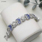 سوار عريضة عبارة عن قطع مربعة متشابكة مع زركون و كتابة بخط كحلي كلمة قل لون فضي