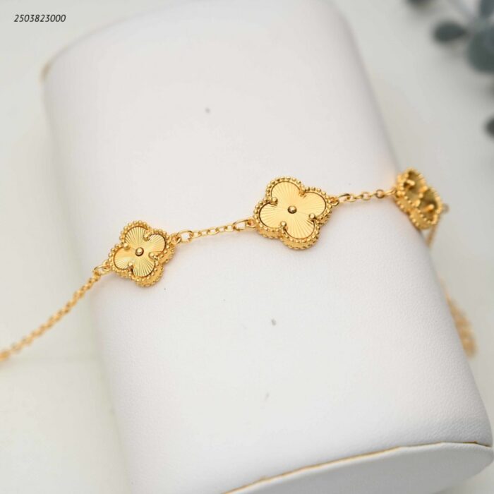 103392005_68e2e739e87fb سوار بتعليقات صغيرة على شكل ورقة برسيم مرصعة لون ذهبي - الصورة 1